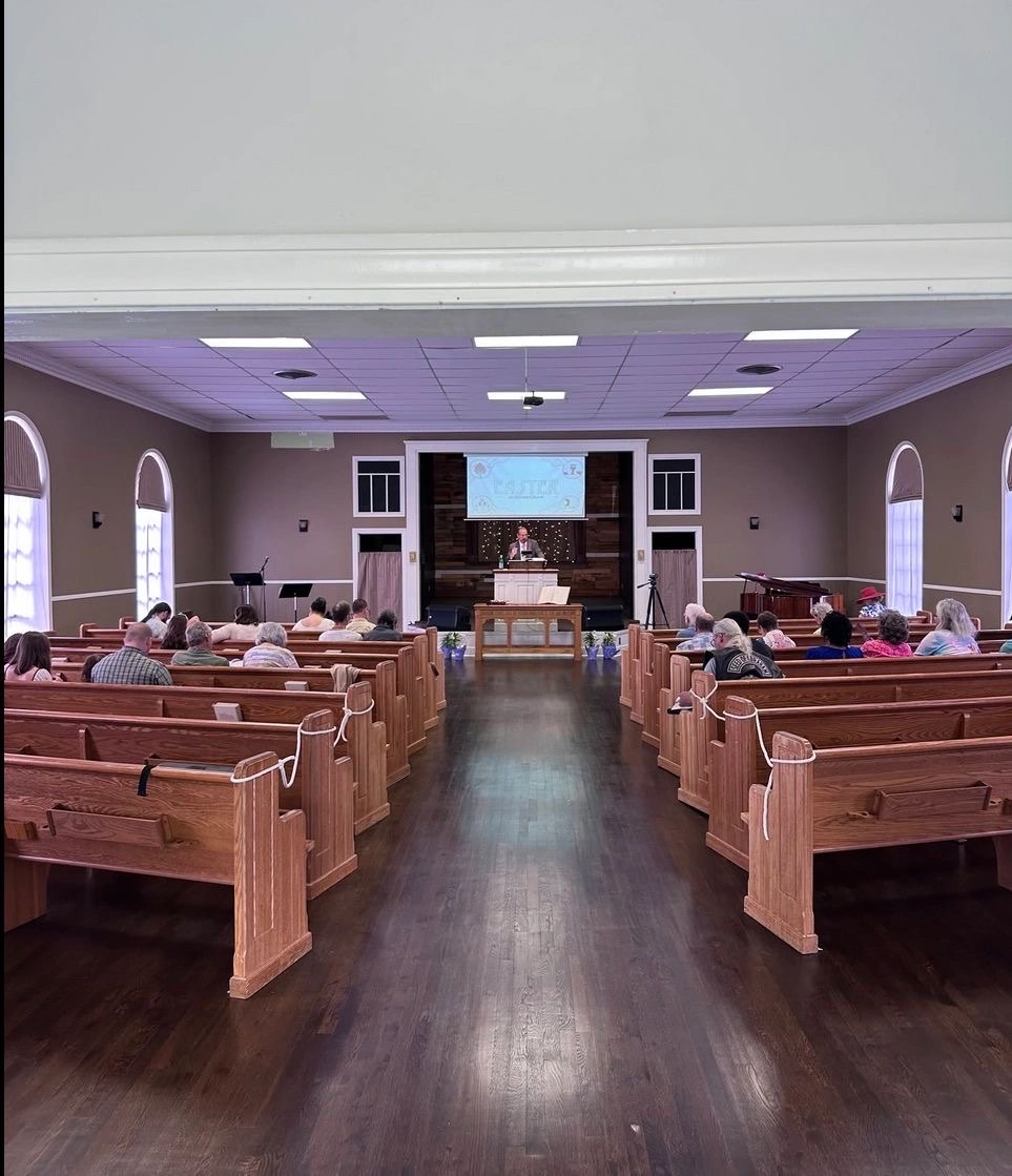 Sunday worship in the Hillcrest sanctuary: wooden pews, arched windows and the pulpit at the front